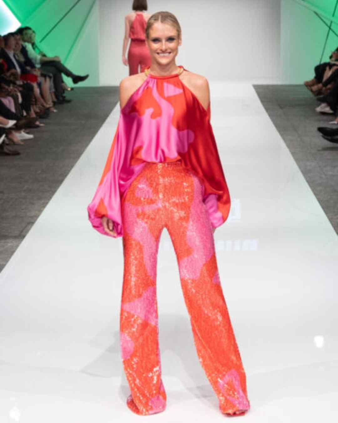 Women on runway wearing pink and organge flowing top and sequinned pants